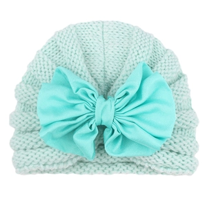 Detail of mint green baby knit hat featuring a large bow and wavy textured patterns