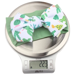Détail du bandeau léger pour bébé avec nœud floral pesant 22,3g sur une balance