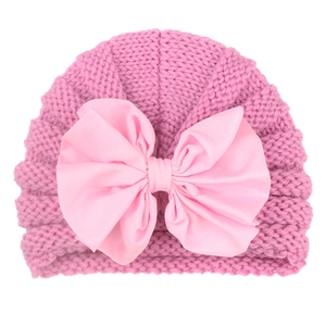 Close-up of deep pink knitted baby turban hat with a large light pink satin bow detail