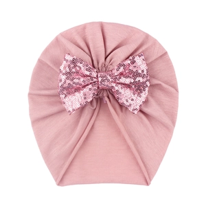 Detail of baby pink turban hat with a large sparkling sequined bow on soft knit fabric