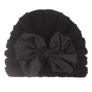 Detailed view of black knitted baby turban hat with a large decorative bow