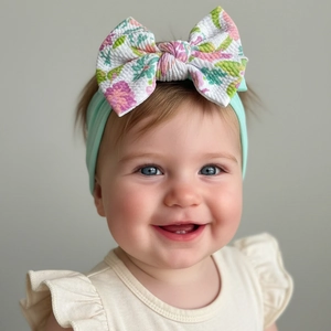 Détail d'un bandeau bébé en nylon vert menthe avec un gros nœud à motif floral