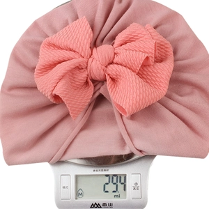 Detail showing soft pink baby headband texture and waffle bow on a scale weighing 29g