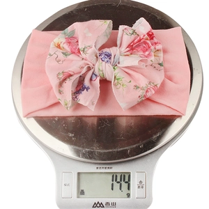 Bandeau bébé rose à nœud floral en nylon doux pesant environ 14,4 grammes sur une balance