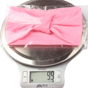 Detail view of a soft pink knotted nylon baby headband on a digital scale weighing 9.9g