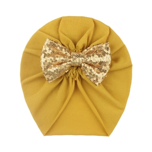 Detail of baby turban hat in ginger yellow with a large sparkling gold sequin bow