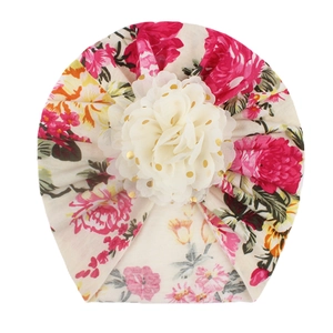Detail of floral baby hat featuring a large white chiffon flower with golden dots
