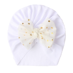 Macro detail of white ribbed baby turban hat with a gold polka dot chiffon bow