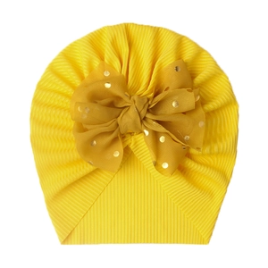 Detail of baby turban hat with ribbed knit fabric and gold polka dot chiffon bow