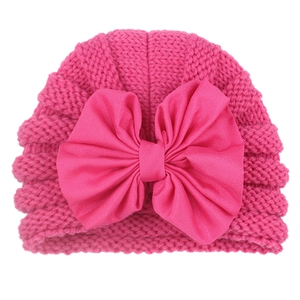 Detailed view of baby girl pink knit hat featuring a large soft fabric bow decoration