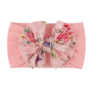 Détail d'un bandeau bébé avec grand nœud à imprimé floral rose sur nylon souple