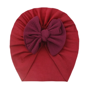 Close-up of deep red waffle textured giant bow on a soft infant turban hat