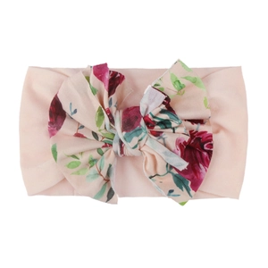 Détail du bandeau en nylon pour bébé avec un grand nœud orné d'un motif de roses rouges