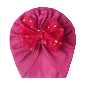 Detail of rose pink ribbed baby beanie featuring a large mesh bow with gold dots
