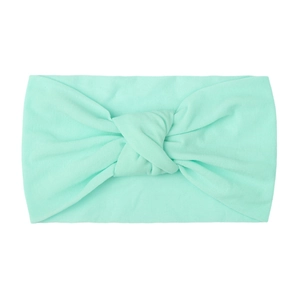 Detail view of a soft mint green nylon knotted headband for babies on white background