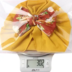 Close-up of lightweight yellow baby headband with floral bow weighing 30.2g on scale