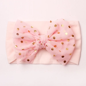 Détail du bandeau en dentelle pour bébé avec pois dorés sur tissu en nylon rose doux