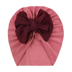 Macro detail of soft ribbed baby turban hat with a large deep wine red bow decoration