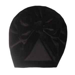 Close-up of black velvet baby hat showing large decorative bow and soft fabric texture