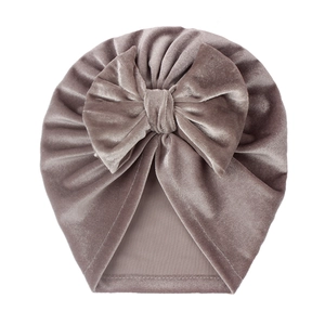 Detail of soft velvet baby hat with large decorative bow in dusty rose color