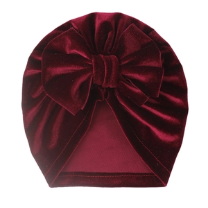 Detail of burgundy velvet baby turban hat with a large bow showing smooth texture