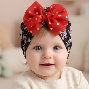 Detailed close-up of soft floral baby turban hat with a large red polka dot bow decoration