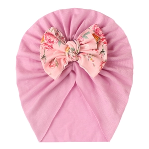 Detail of soft pink baby hat with large floral bow print and fine knit texture