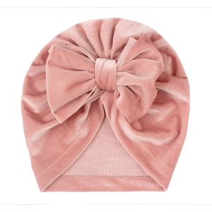 Pink velvet baby turban hat with a large bow decoration on white background