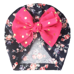 Detail of baby turban hat with pink sequin bow and floral print on dark blue fabric