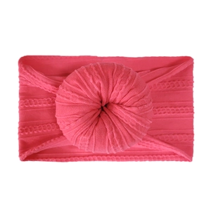 Soft peach pink knitted baby headband with a large decorative donut-shaped knot design