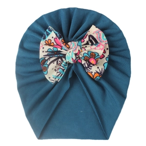 Close-up of baby turban hat in dark teal cotton with a large floral print bow detail