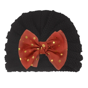 Close-up of black baby turban hat with a large red gold-dotted tulle bow decoration