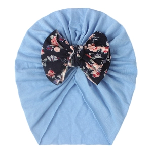 Detail of baby turban hat in light blue with a large floral print bow decoration
