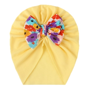 Detailed view of yellow baby turban hat with a large colorful floral print bow accent