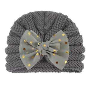 Detail of grey baby knitted turban hat featuring a large mesh bow with gold sequins