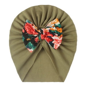 Close-up of olive green ribbed baby turban hat with a large floral print bow decoration