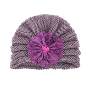 Detailed macro view of the purple knit baby hat featuring a large layered fabric flower