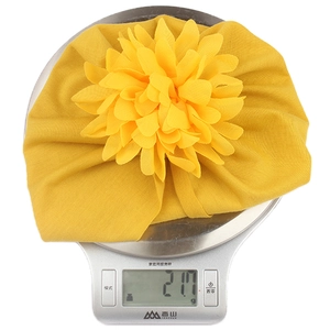 Détail montrant le poids de 21,7g d'un bonnet turban jaune pour bébé avec fleur