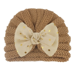 Detail of baby turban hat featuring a knitted design and oversized polka dot bow