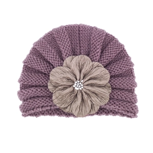 Close-up of the large fabric flower and pearl bead on the knit purple baby hat