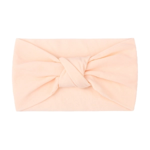 Detail of soft peach knotted baby headband made of stretchy knit fabric texture