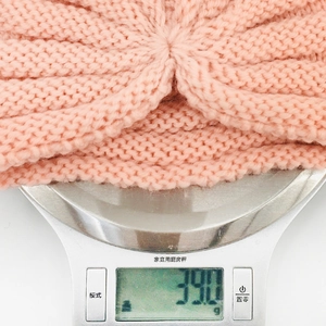 Digital scale showing pink knitted baby hat weighing 39.0 grams for lightweight comfort