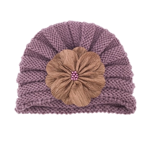 Detailed texture of baby knit hat with large brown fabric flower and purple bead core
