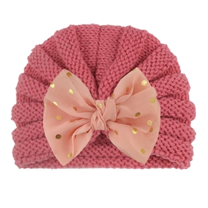 Pink chunky knit baby turban hat featuring a large chiffon bow with gold polka dot sequins