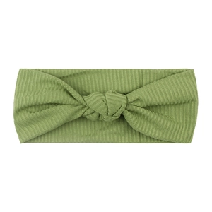 Close-up of grass green ribbed knit baby headband with a knotted bow design on white background