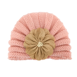 Detailed shot of baby knit hat featuring a large fabric flower and white pearl beads