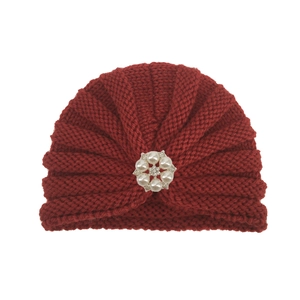 Détail du turban en tricot bordeaux pour bébé avec broche fleur en perles et strass