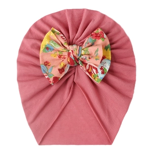 Close-up of pink baby turban hat with a large floral print bow and pleated knit texture