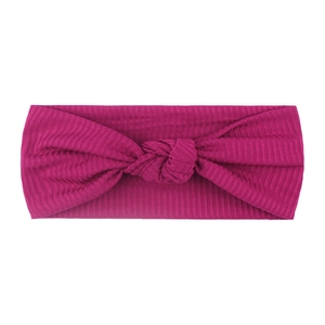 Close-up of rose red ribbed knit baby headband featuring a decorative center knot detail