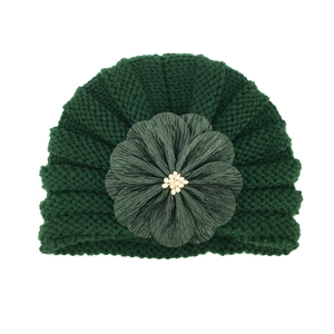 Detailed texture of dark green knit baby hat with large satin flower and pearl beads